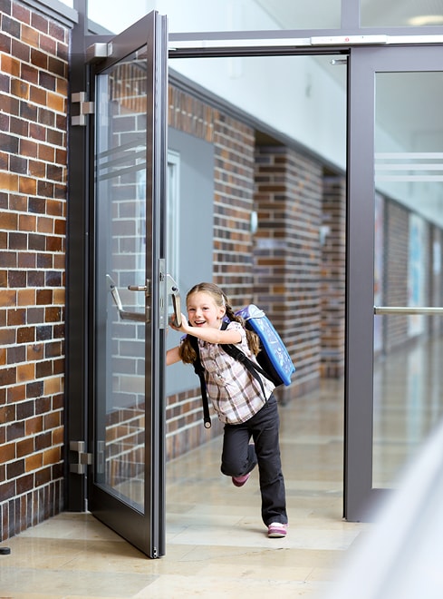 Lachendes Schulkind läuft durch geöffnete Strussnig Brandschutztür