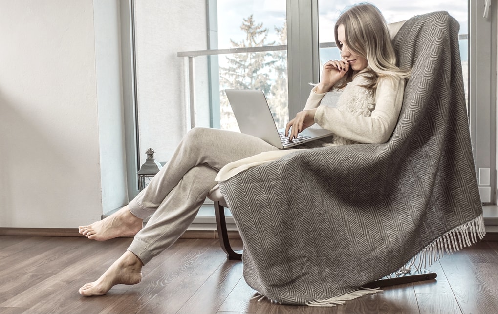 Frau mit Laptop sitzt in Schaukelstuhl vor Strussnig Hebe-Schiebetür