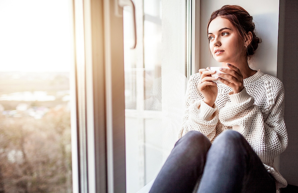 Frau mit Tasse vor Fenster