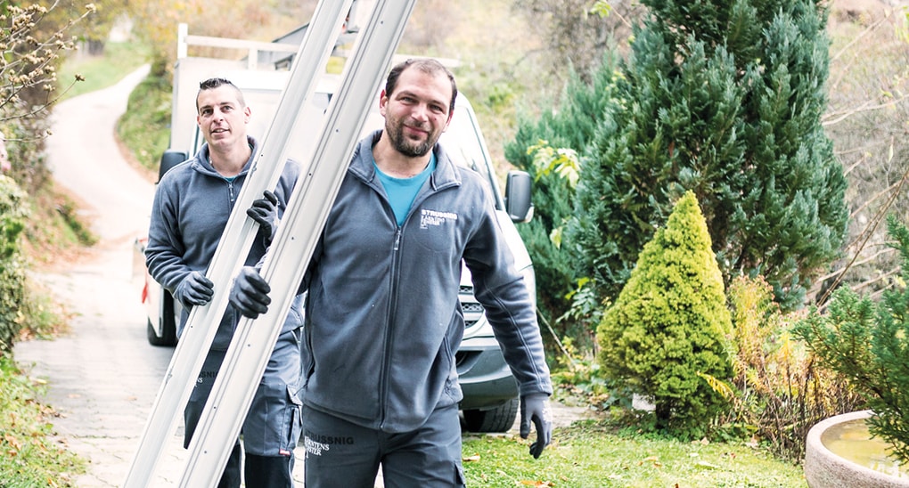 Strussnig-Mitarbeiter tragen einen Fensterrahmen und bereiten die Montage vor