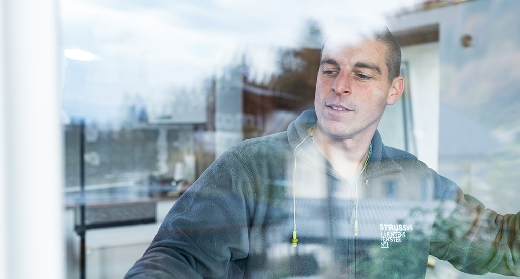 Strussnig-Mitarbeiter blickt bei der Montage durch das neue Fenster