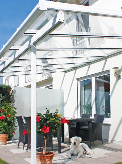 Glasüberdachte Terrasse mit Sitzgarnitur und Hund davor