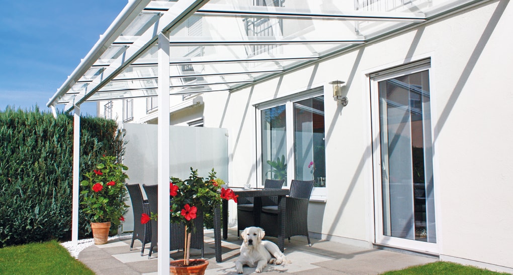 Glasüberdachte Terrasse mit Sitzgarnitur und Hund