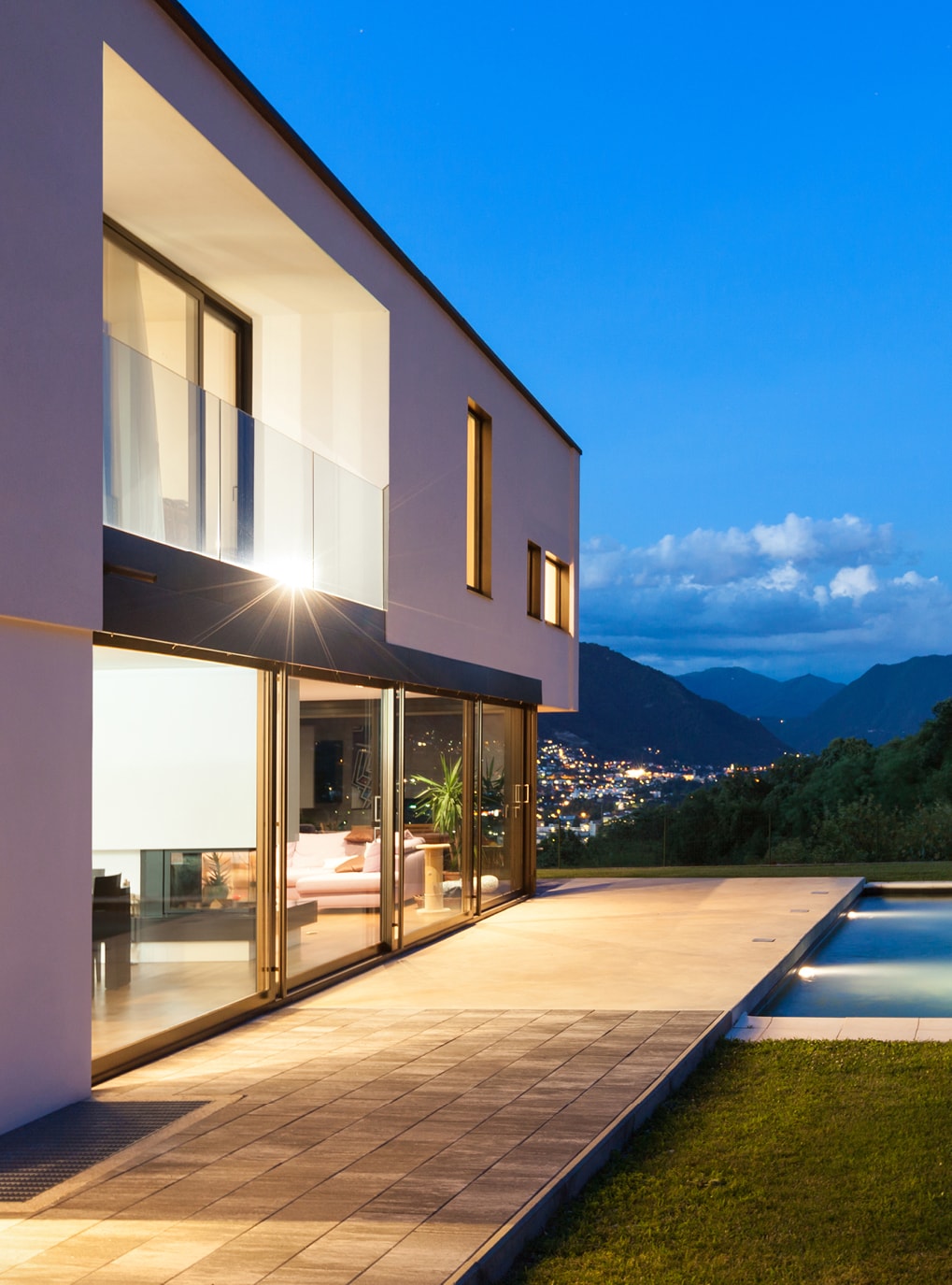 Weiße Hausfassade mit Strussnig Holzfenstern vor abendlichem Himmel, Terrasse und Swimmingpool