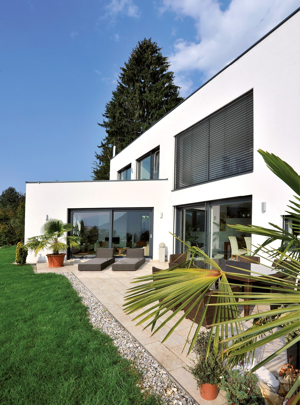 Strussnig Kunststoff-Alu-Fenster (teils mit geschlossenem Sonnenschutz) an weißer Fassade