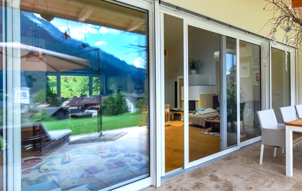 Großflächige Kunststoff-Alu Fenster von Strussnig mit Schiebetürelement, das auf Terrasse führt