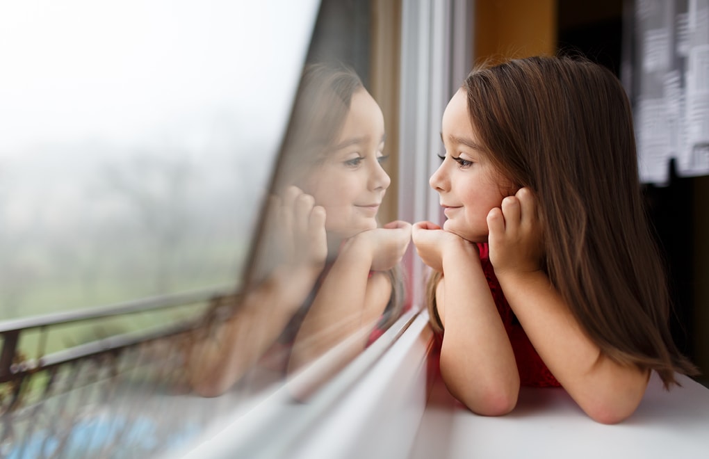 Mädchen blickt durch Fenster nach draußen