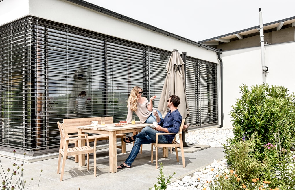 Terrasse mit Strussnig Fenstern mit geschlossenen Rollläden im Hintergrund